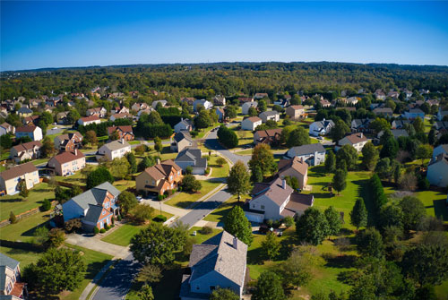 A drone shot of a residential neighborhood on a bright, sunny day.